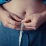 Emagrecer em 1 semana: Foto de uma pessoa utilizando uma fita métrica para medir a barriga.