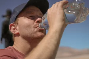 homem tomando garrafa d'agua desidratação no calor